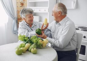 Beautiful old couple prepare food in a kitchen